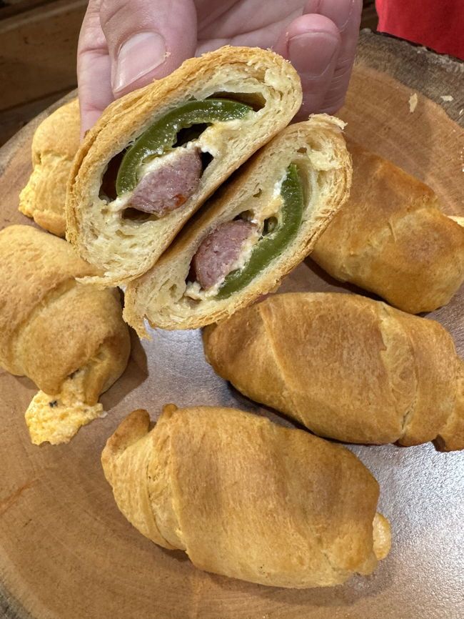 a person holding a sandwich in front of some croissants on a plate