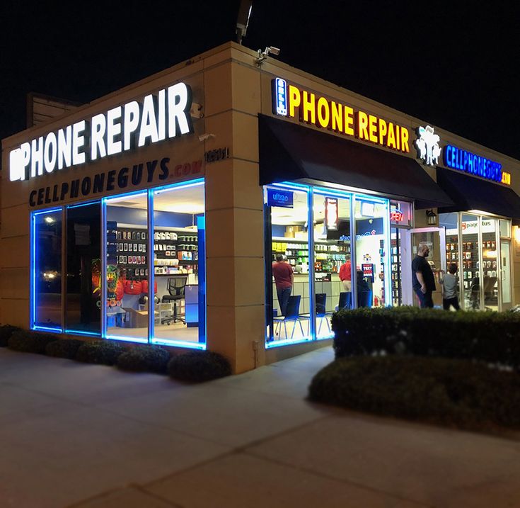 a phone repair store at night with people standing outside