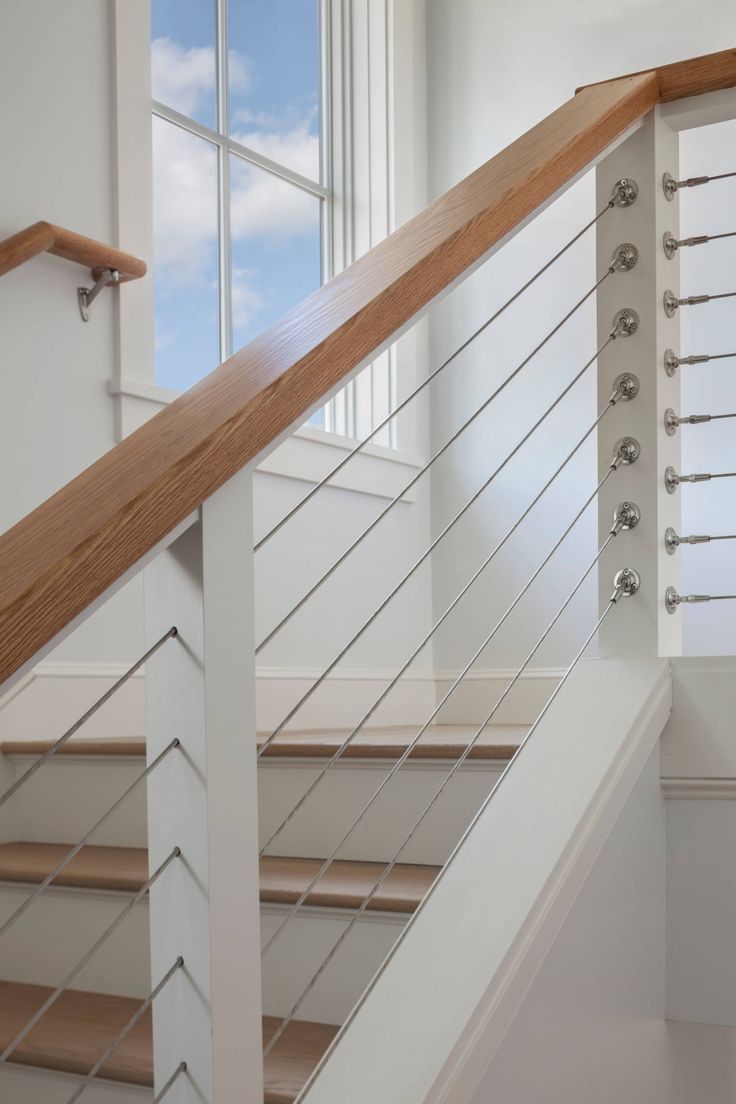 a stair case with glass railing and wood handrails in front of a window