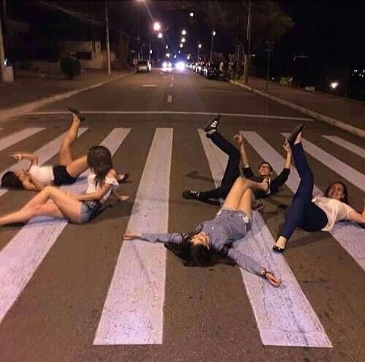 four people laying on the street with their arms in the air