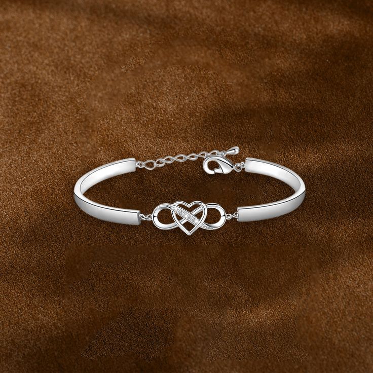 a silver bracelet with two intertwined links on a brown velvet background, close up