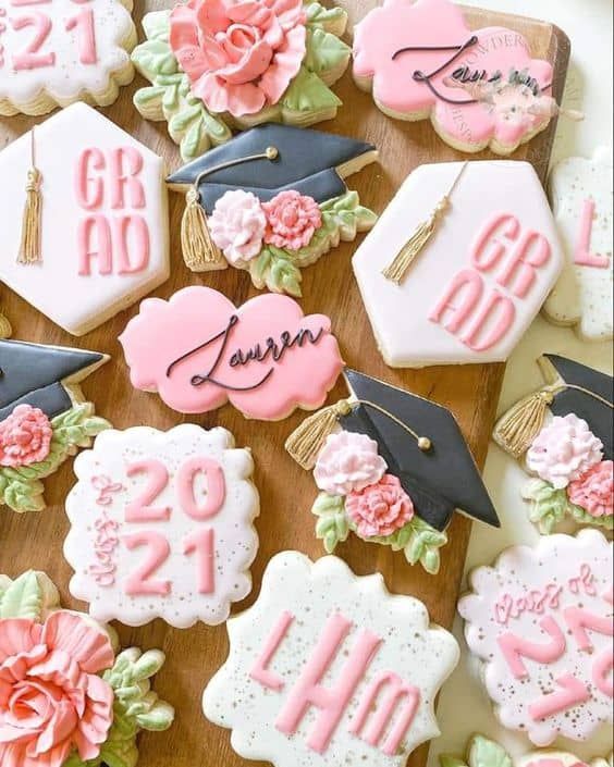 decorated cookies with graduation caps and flowers are arranged on a wooden board in the shape of numbers