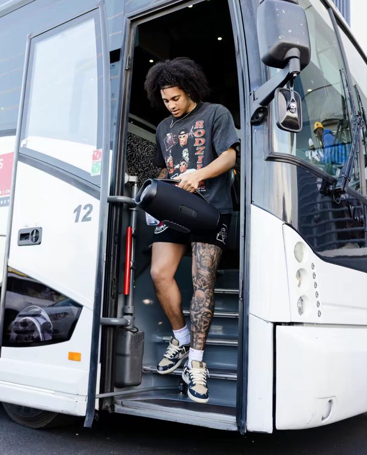 a man with tattoos standing in the doorway of a bus