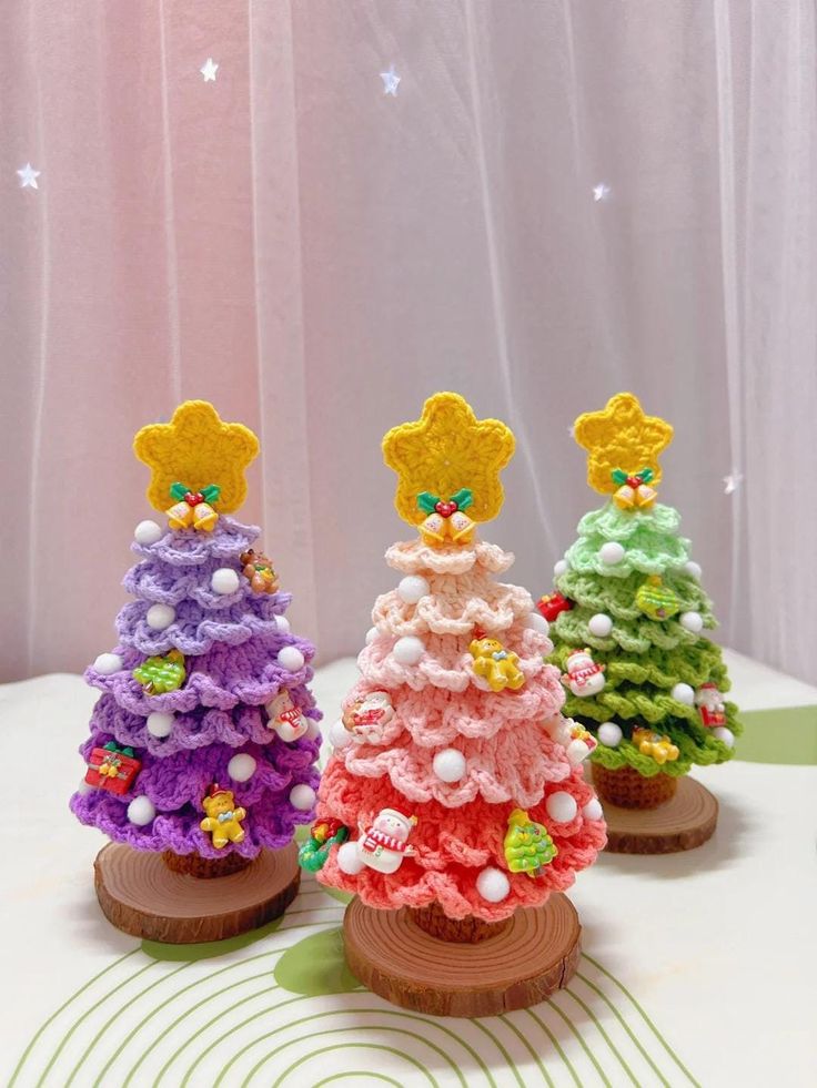 three small crocheted christmas trees sitting on top of a table