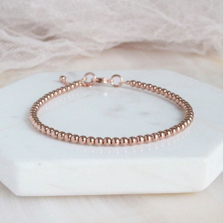 "Rose Gold Bead Minimalist Bracelet Beautiful dainty rose gold-filled bead (3mm) bracelet with a rose gold plated clasp and completed with a 1\" extender rose gold-filled chain. This bracelet is created with rose gold-filled beads and not plated beads. Each bracelet will arrive in a box tied with a ribbon perfect for gift giving. Also, included will be a polish pad, anti-tarnish bag with an anti-tarnish tab for storing. Please read my policies before placing an order. Convo me if you have any qu Rose Gold Beaded Bracelet With Round Beads, Minimalist Rose Gold Beaded Bracelets As Gift, Adjustable Rose Gold Beaded Bracelets, Rose Gold Beaded Bracelets As Gift, Rose Gold Bracelet With Tiny Round Beads, Elegant Rose Gold Charm Bracelet With Round Beads, Elegant Rose Gold Beaded Bracelets With Tiny Beads, Elegant Rose Gold Bead Charm Bracelet, Dainty Rose Gold Beaded Bracelets