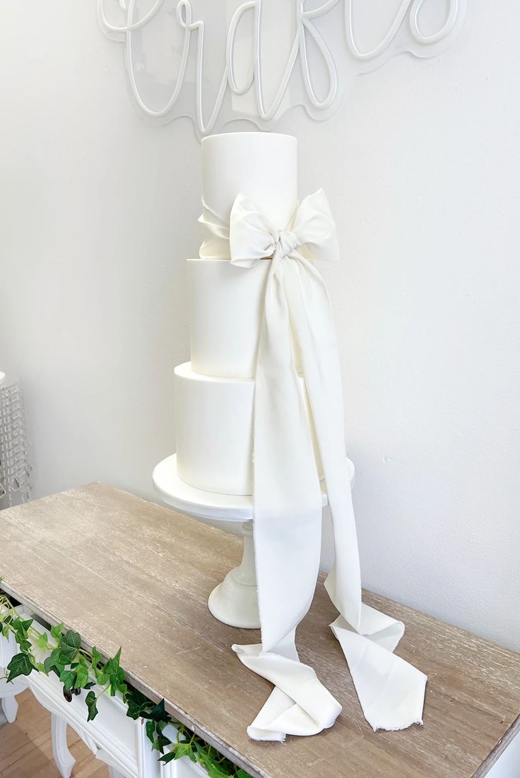 a white wedding cake sitting on top of a wooden table