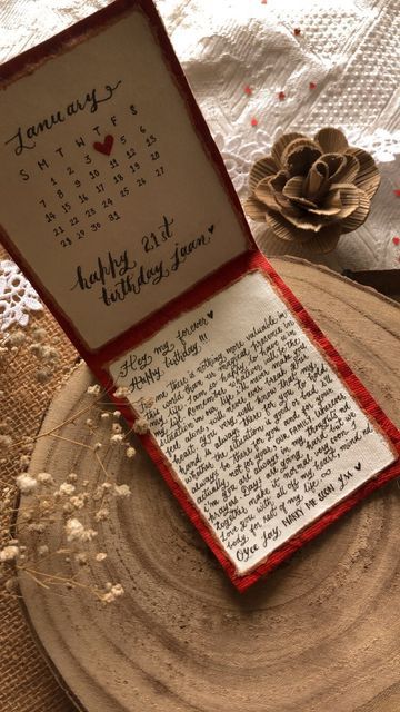 an open box with writing on it sitting on top of a wooden table next to a pine cone