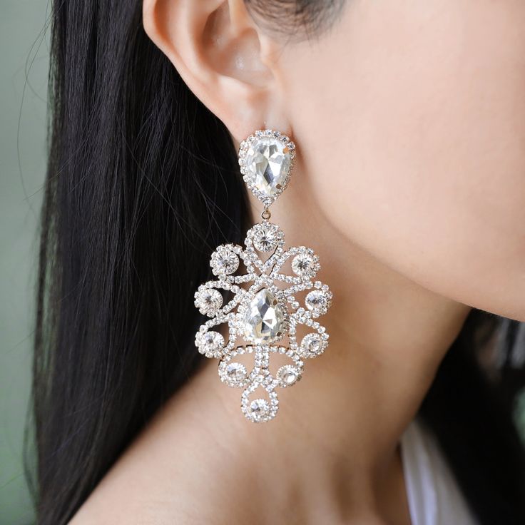 With these sparkling masterpiece jewelry on your ears, you'll light up the whole room like the sun rising over a skylight. Shoulder length and lightweight, wear these stunning chandelier statement earrings with a casual white tee for that extra oomph of bling or an off the shoulder dress/blouse to catch anyone's eye. Size• Post backing earrings.• Length: 3.25 in (8.26 cm)• Width: 1.75 in (4.45 cm) QualityLarge iridescent shiny rhinestone gems surrounded by mini stones in a teardrop chandelier de Crystal Drop Chandelier Earrings, Dazzling White Crystal Earrings, Dazzling White Sparkling Chandelier Earrings, White Crystal Teardrop Earrings With Sparkle, White Crystal Teardrop Earrings With Sparkling Detail, White Sparkling Crystal Teardrop Earrings, Sparkling White Crystal Teardrop Earrings, Diamond White Crystal Chandelier Dangle Earrings, Diamond White Crystal Chandelier Earrings