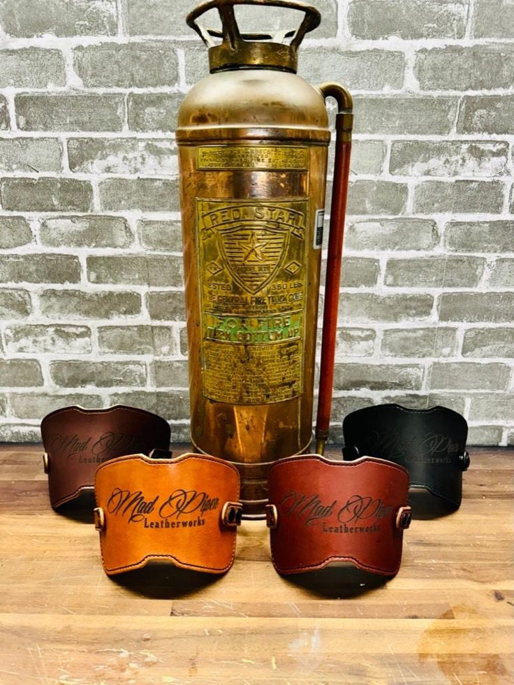 four different colored leather cups sitting next to an old fashioned ketchup bottle on top of a wooden table