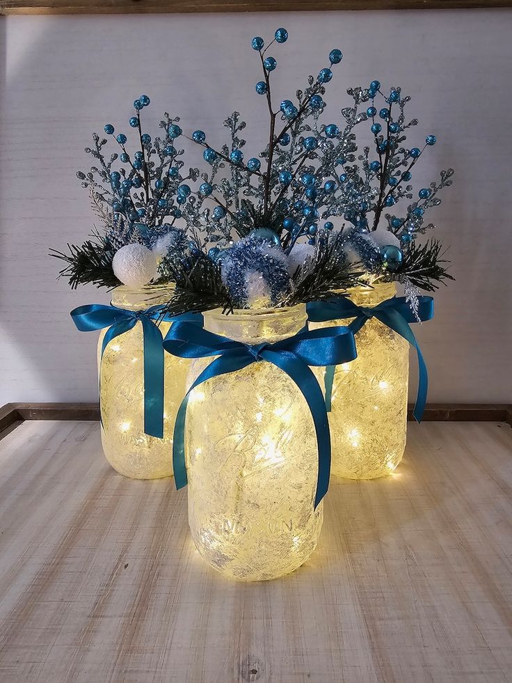 lighted mason jars with blue ribbon and flowers in them