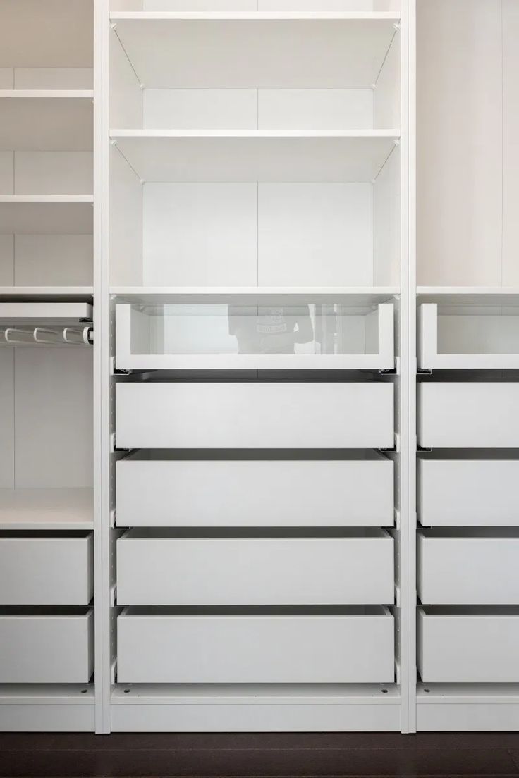 an empty white closet with drawers and shelves