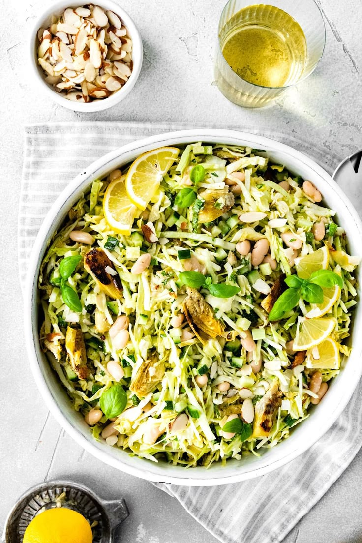 a white bowl filled with salad next to lemons and nuts