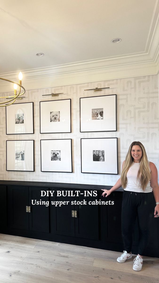 a woman standing in front of a wall with pictures on it