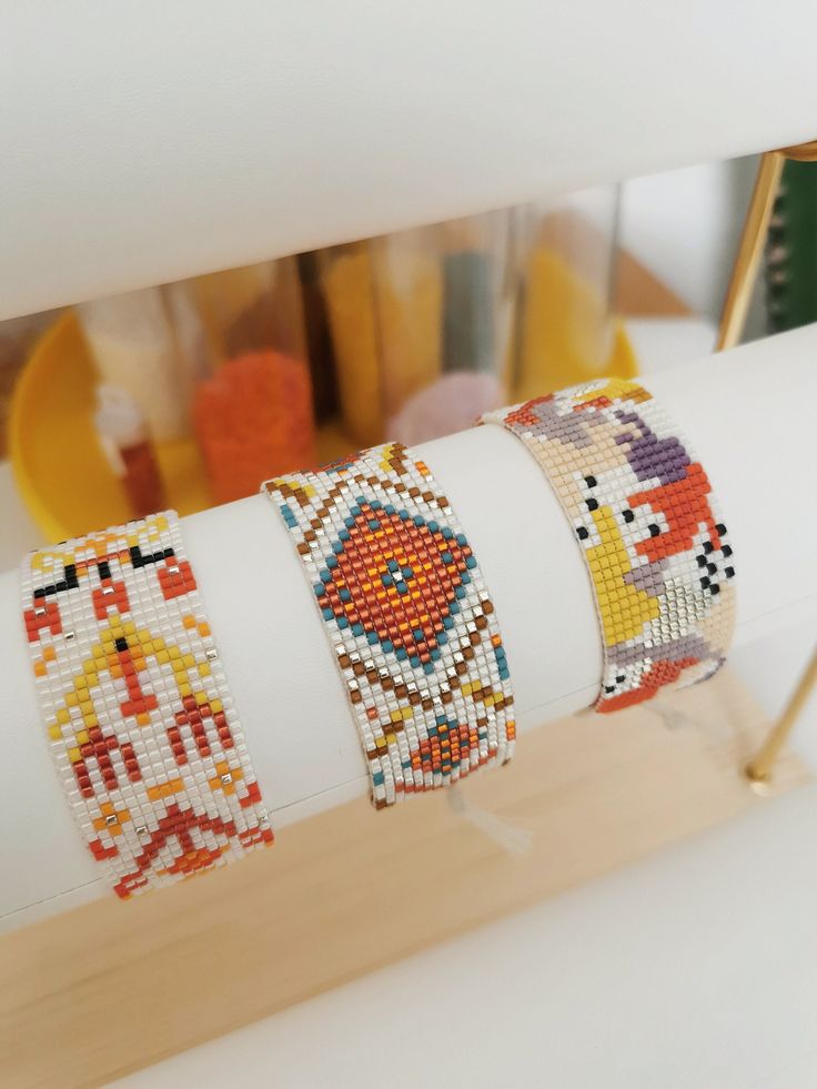 four bracelets are sitting on top of each other in front of a shelf with beads