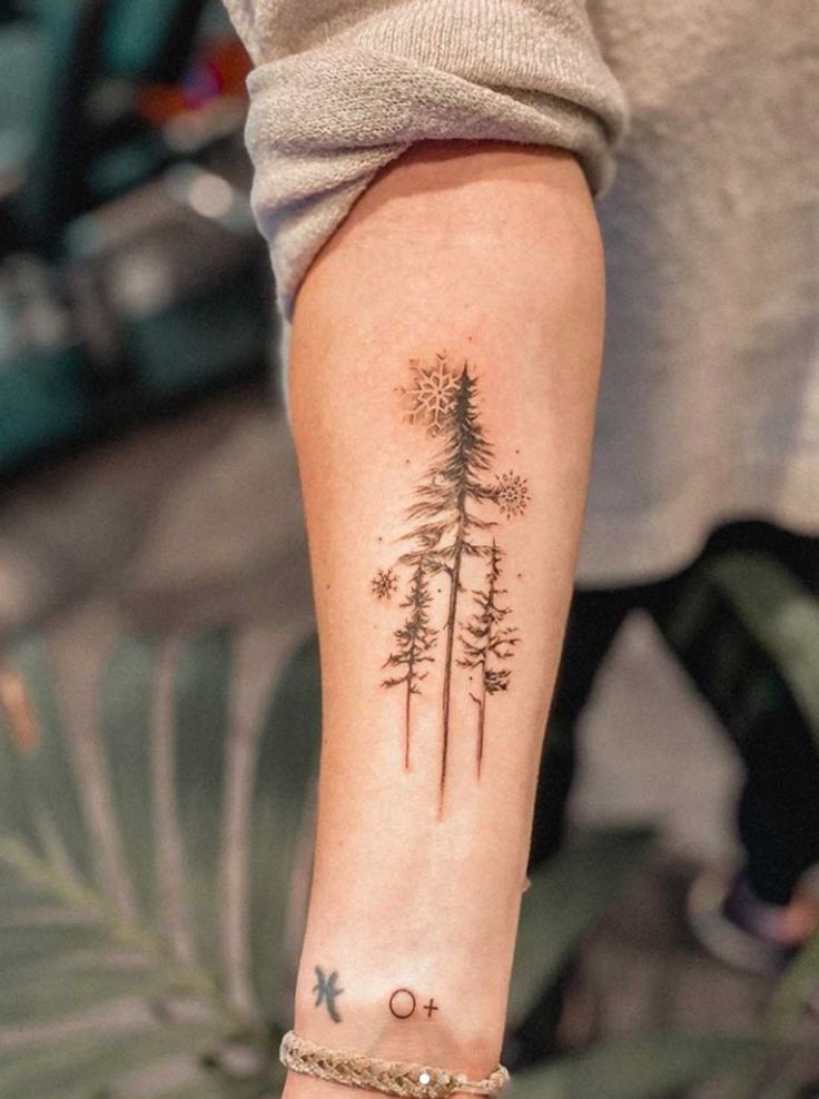 a woman's arm with a pine tree tattoo on it