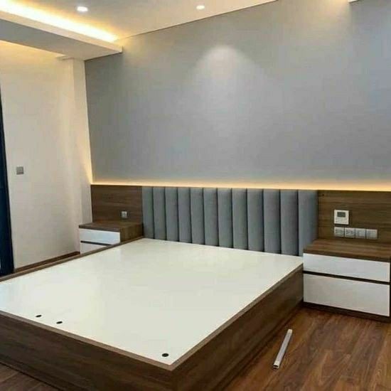 an empty bed in a room with wood flooring