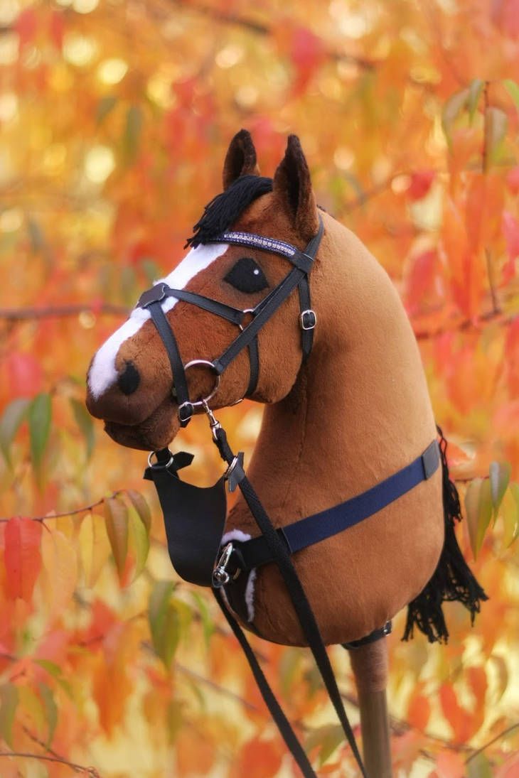 a stuffed horse is tied to a tree branch in front of fall foliage and leaves