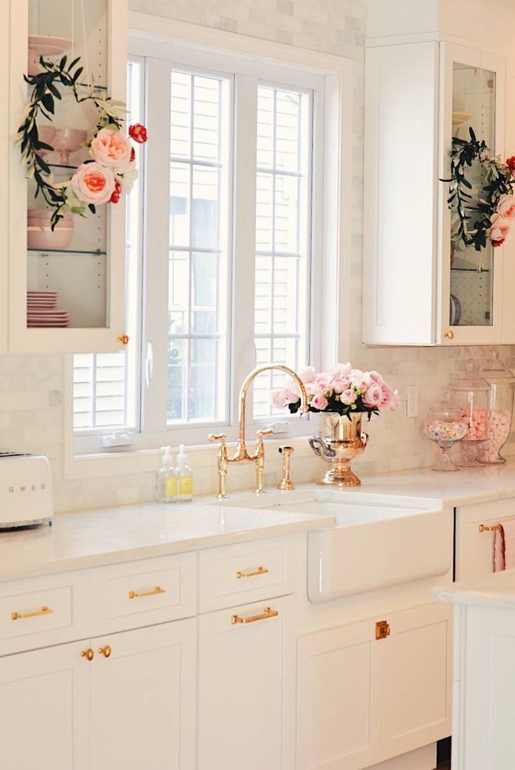 a kitchen with white cabinets and pink flowers