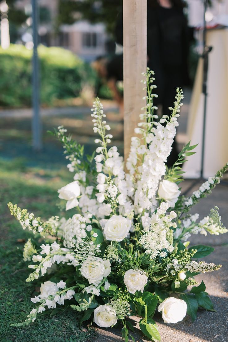 a bouquet of white flowers sitting on top of a grass covered ground next to a pole