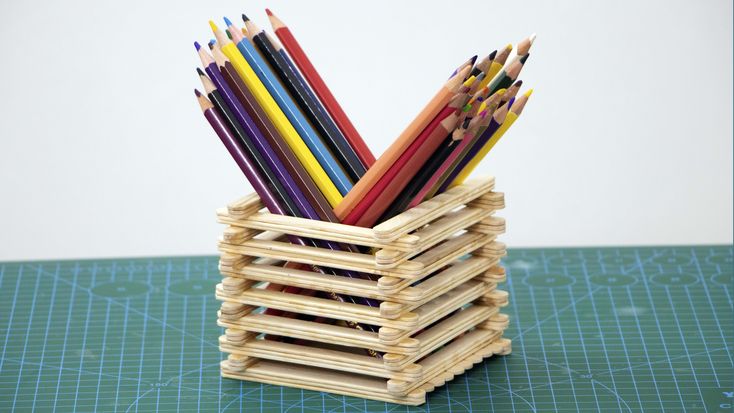 a stack of colored pencils sitting on top of a green table next to a pair of scissors