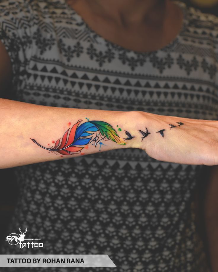 a woman's arm with a colorful feather tattoo on the left side of her arm