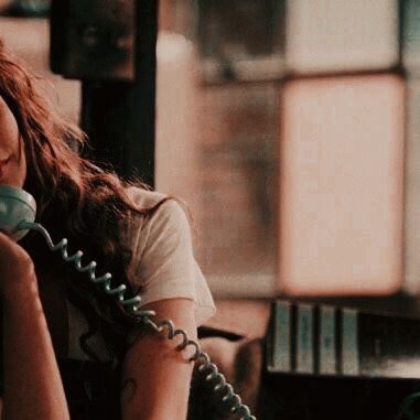 a woman talking on the phone while sitting at a table