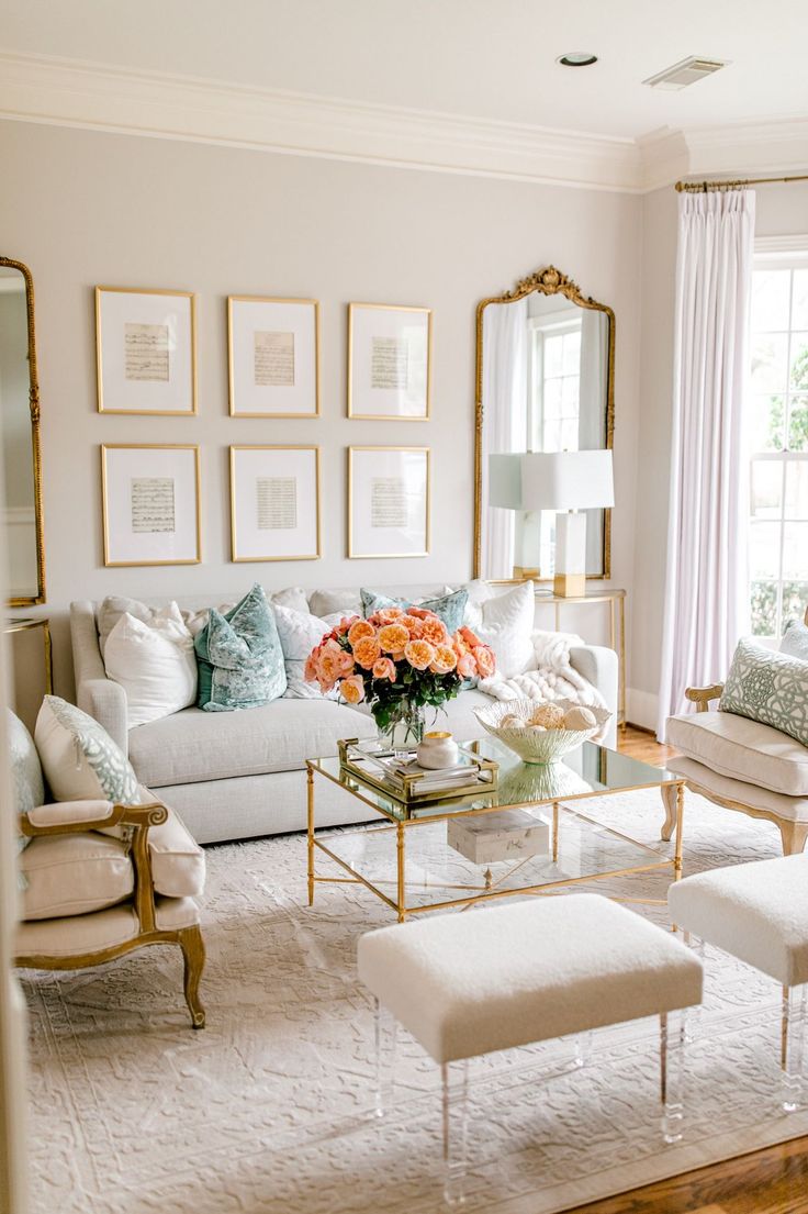 a living room filled with white furniture and lots of pictures on the wall above it