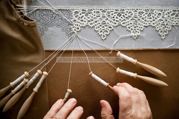 two hands are working on an art project with wooden dowels and thread spools