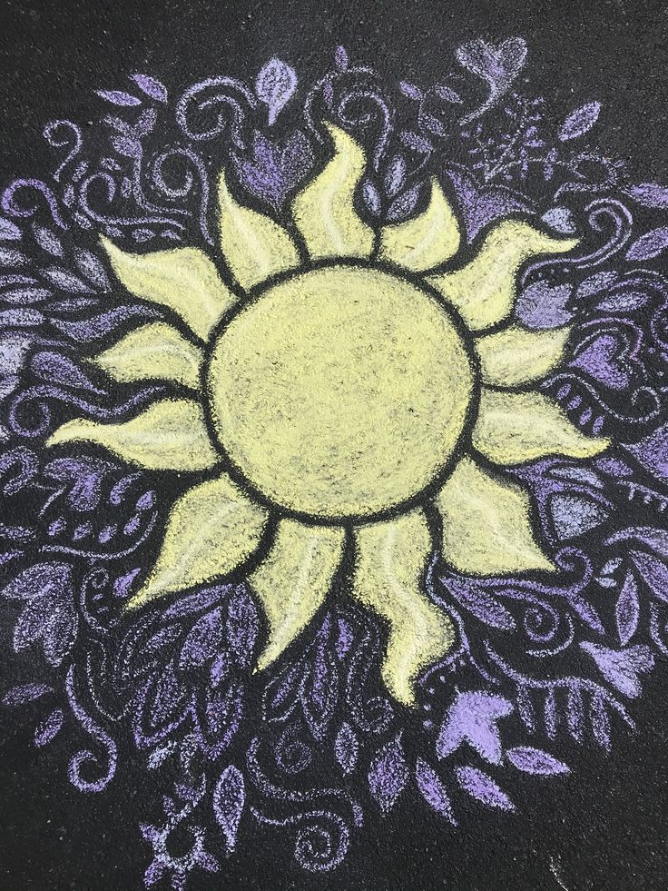 a chalk drawing of a sun with swirls in the center on a black surface