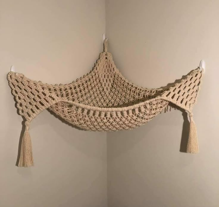 a crocheted hammock hanging on the wall with tassels attached to it