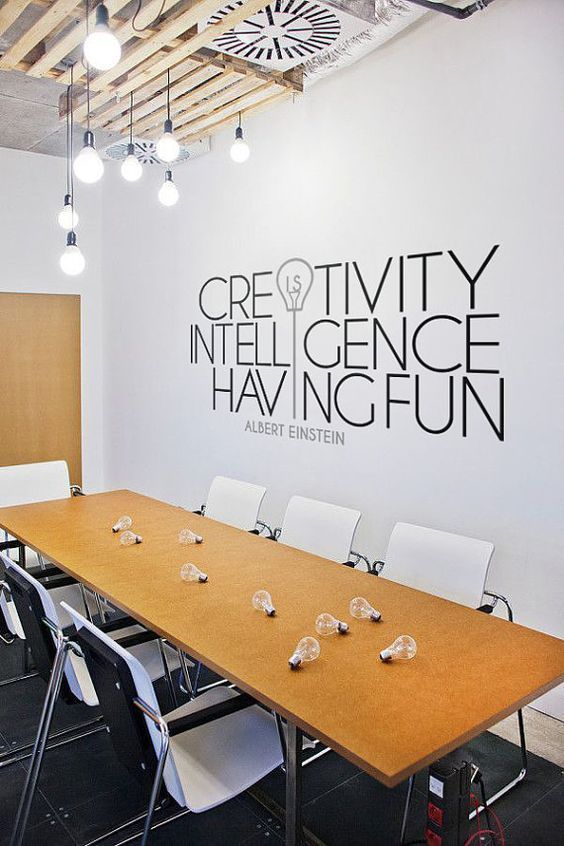 a conference room with a long table and chairs in front of a wall that says creativity