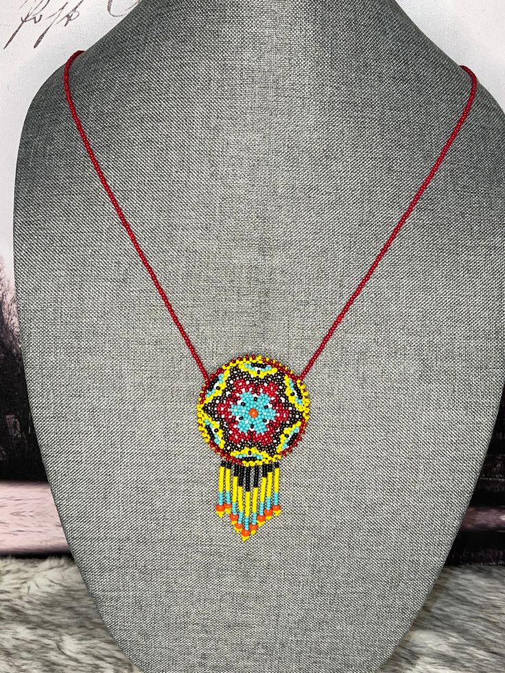 a beaded necklace on a mannequin with a red string and beads hanging from it