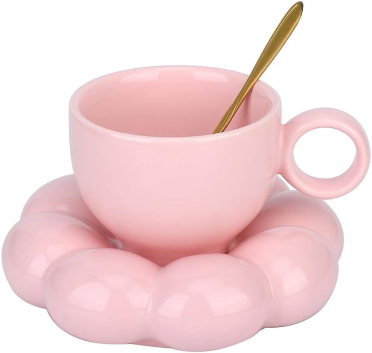 a pink cup and saucer with a gold spoon in it on a white background