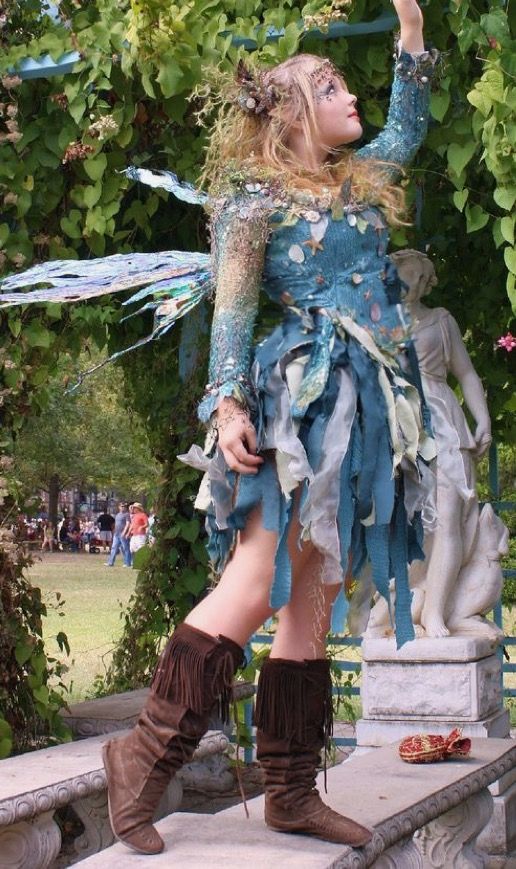 a woman dressed up like a fairy standing on some steps in front of a tree