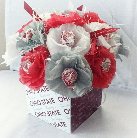 a bouquet of red and white flowers sitting on top of a box filled with chocolates