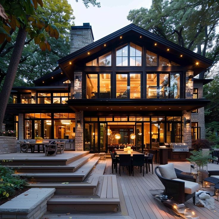 a large house with lots of windows and stairs leading to the front door is lit up at night