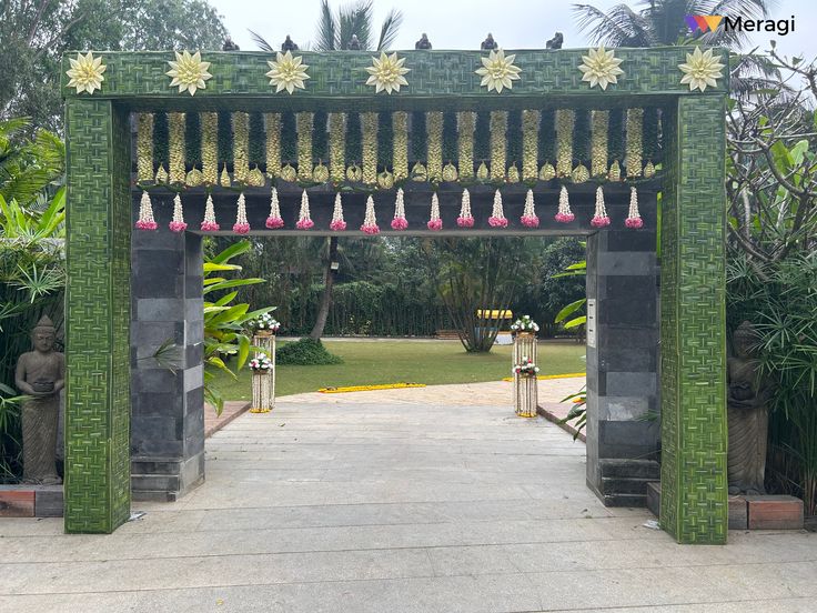 an entrance to a garden with statues and flowers