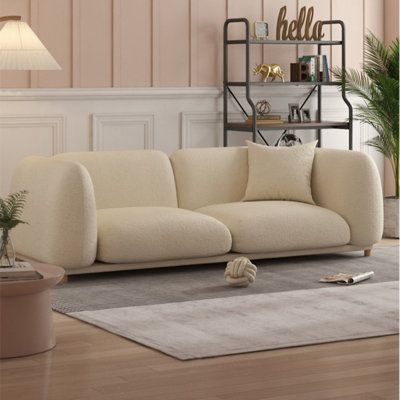 a white couch sitting on top of a hard wood floor next to a potted plant