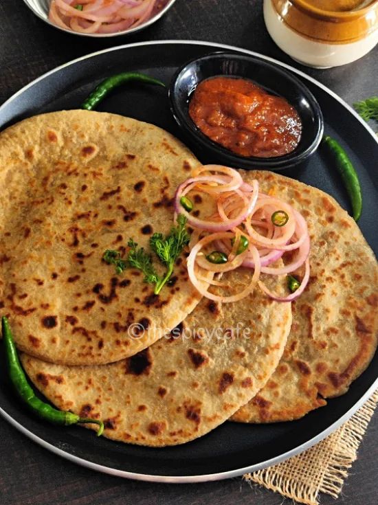 three flat breads on a plate with onions and sauce