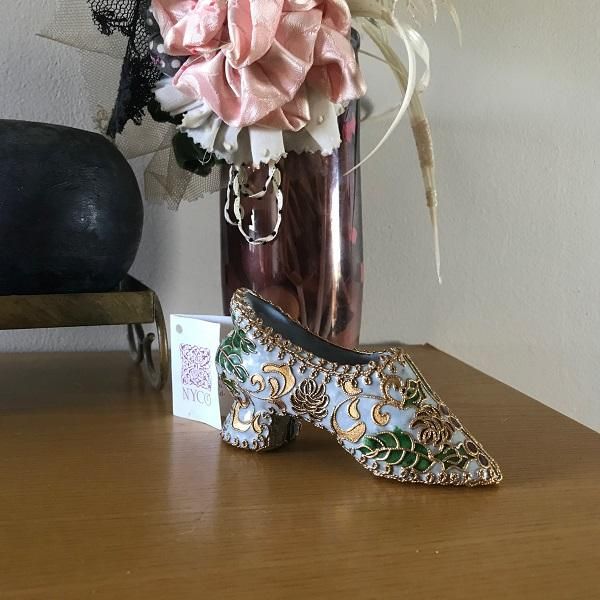 a pair of high heeled shoes sitting next to a vase with flowers in it