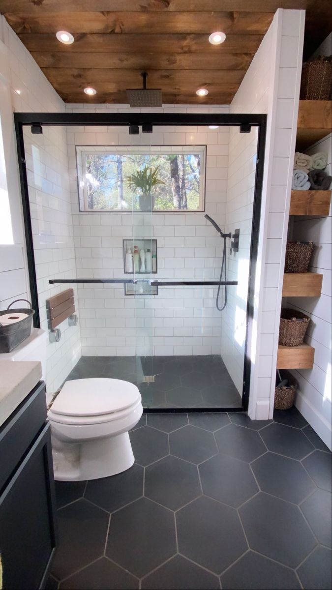 a white toilet sitting inside of a bathroom next to a sink and shower head mounted on a wooden ceiling