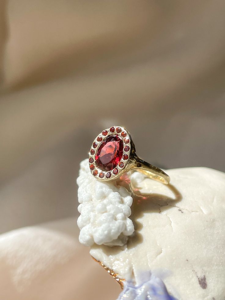 This Heirloom ring is a sacred treasure to cherish - designed to embody an ancient French relic. Featuring a stunning 8x6mm Garnet, surrounded by a halo of Garnet stones. Hand-carved in 14k yellow gold with a deliberately matte finish, this piece emanates an ancient Byzantine vibration, energetically empowering you with deeply driven strength, willpower and recognition that you are an unstoppable force, a cosmic miracle, and a Divine creator of your own destiny. *Garnet: a powerful passion stone Heirloom 14k Gold Halo Ring, Heirloom 14k Gold Halo Cluster Ring, Heirloom 14k Gold Cluster Ring With Halo, Vintage Yellow Gold Halo Jewelry, Heirloom Halo Cluster Ring In 14k Gold, Gold Teardrop Halo Ring, Heirloom Gold Cluster Ring With Halo, Heirloom Yellow Gold Ruby Ring With Halo Design, Heirloom Style Gold Cluster Ring With Halo