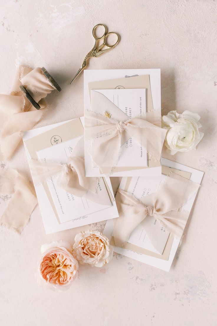 the wedding stationery is laid out on top of each other with flowers and scissors