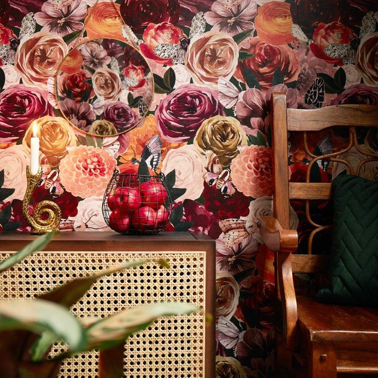 a room with flowers on the wall next to a wooden chair and table in front of it