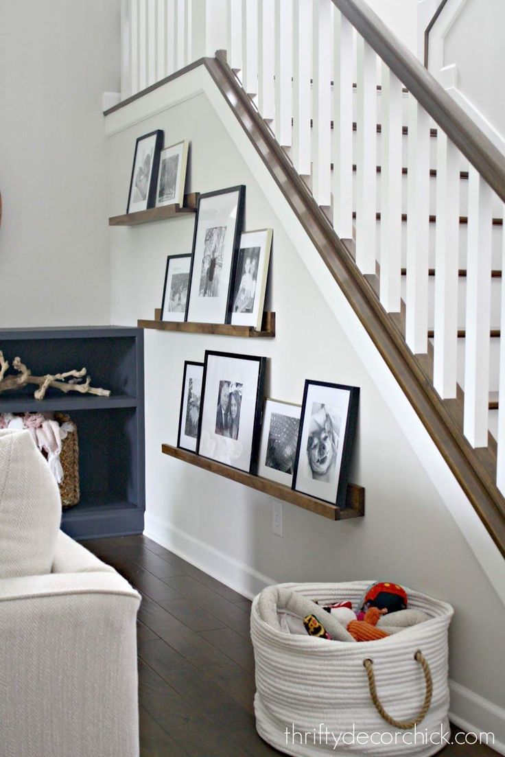 a living room with pictures on the wall and a basket in front of it next to stairs