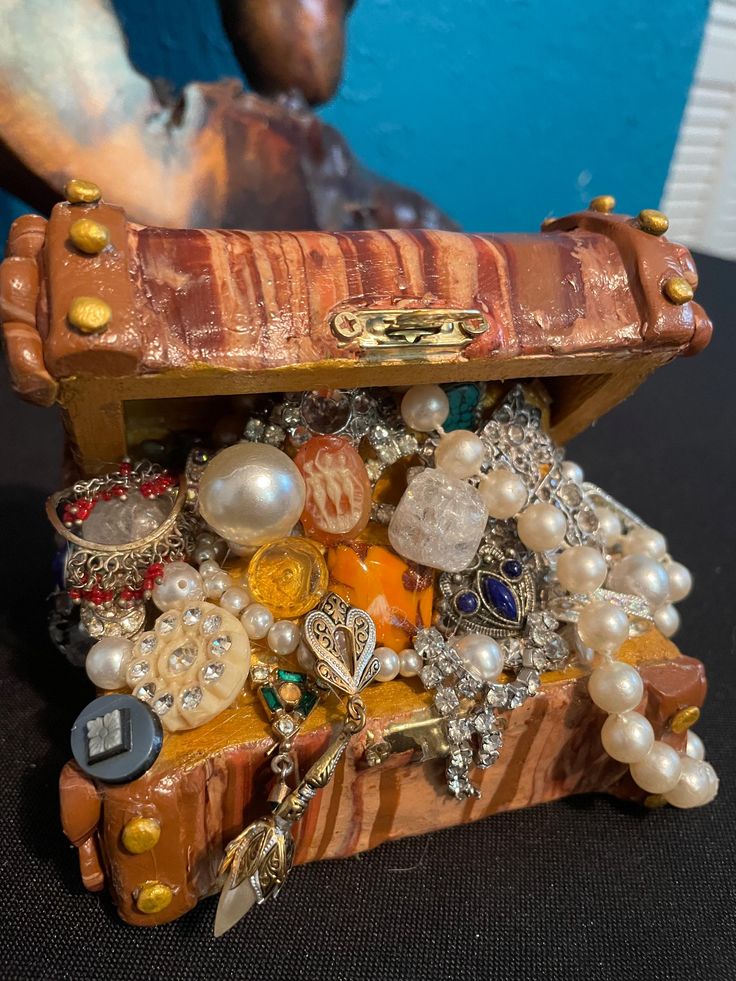 a small wooden box filled with lots of different types of beads and jewelry on top of a table