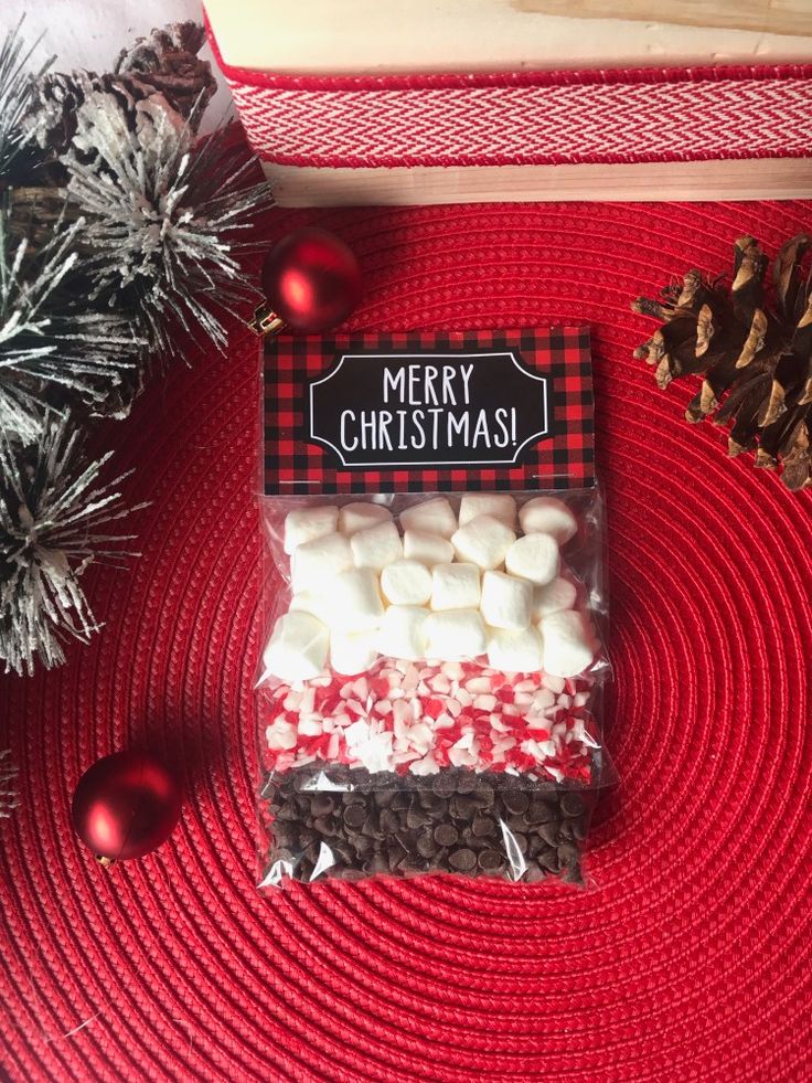 a bag of marshmallows sitting on top of a red place mat next to christmas decorations