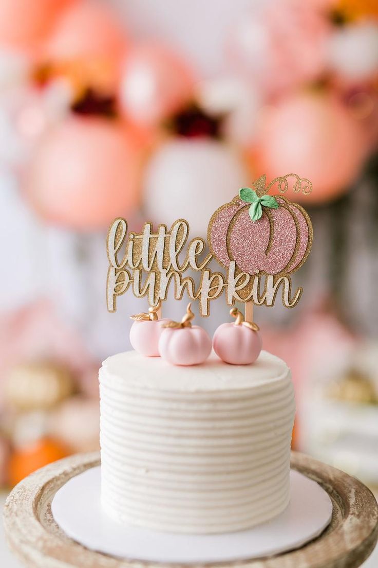 a little pumpkin cake topper sitting on top of a white cake