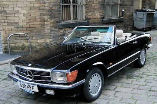 a black mercedes benz convertible parked in front of a brick building