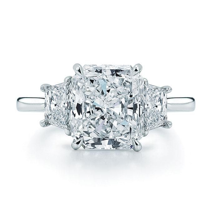 a three stone diamond ring with two princess cut diamonds on the sides and side stones